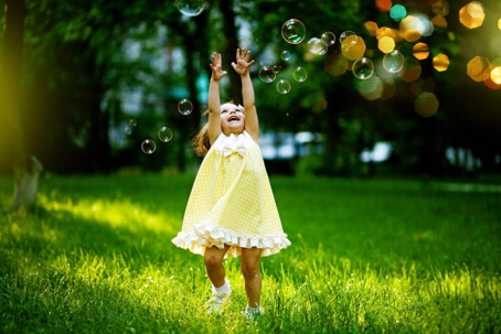 little girl in a yellow dress playing with bubbles