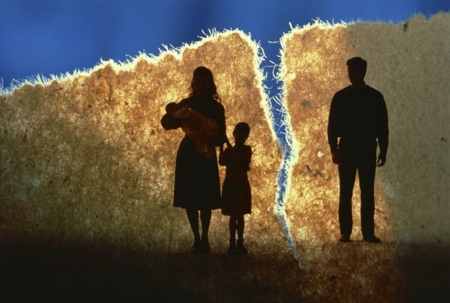 A back-lit and torn piece of paper with a mother, baby, and child on the left side of the tear and the father on the right side.