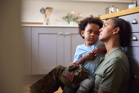 sad service member sitting on the floor with her child