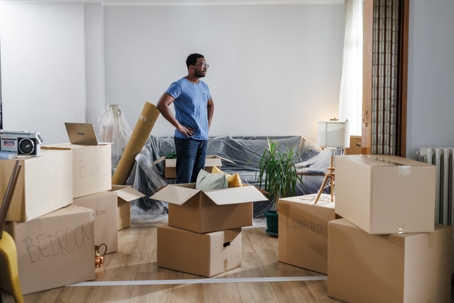 man standing in living room surrounded by moving boxes