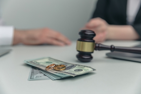 Gavel with a stack of money and wedding rings
